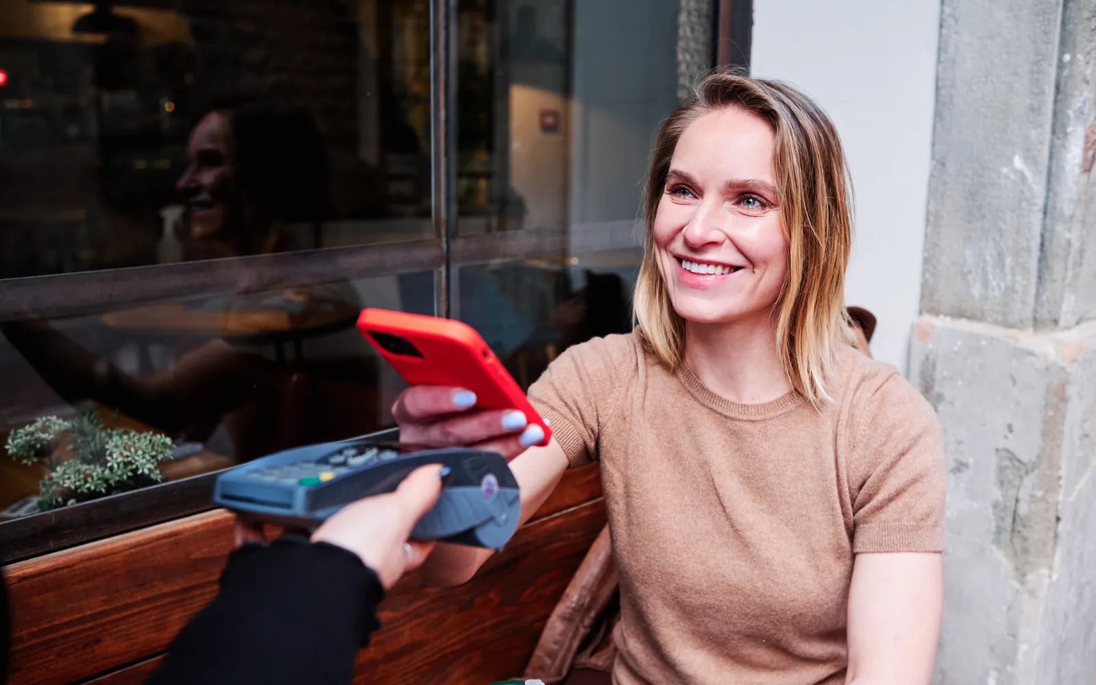 Customer paying with a smartphone at a contactless card reader in a café