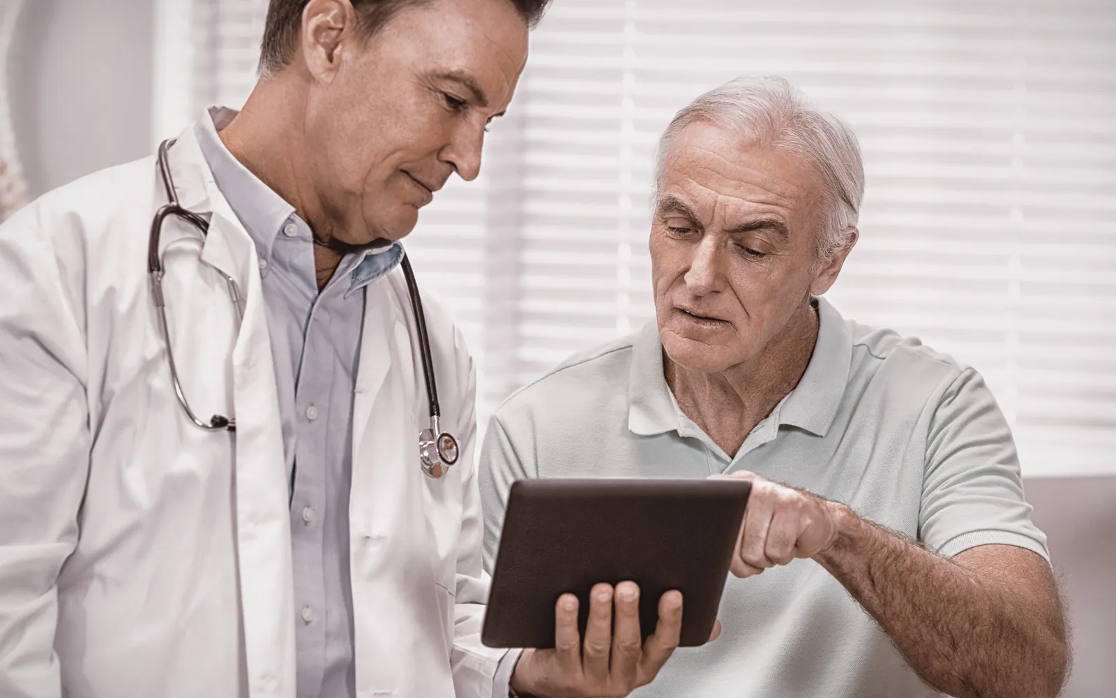 Doctor reviewing health information on a tablet with a senior patient
