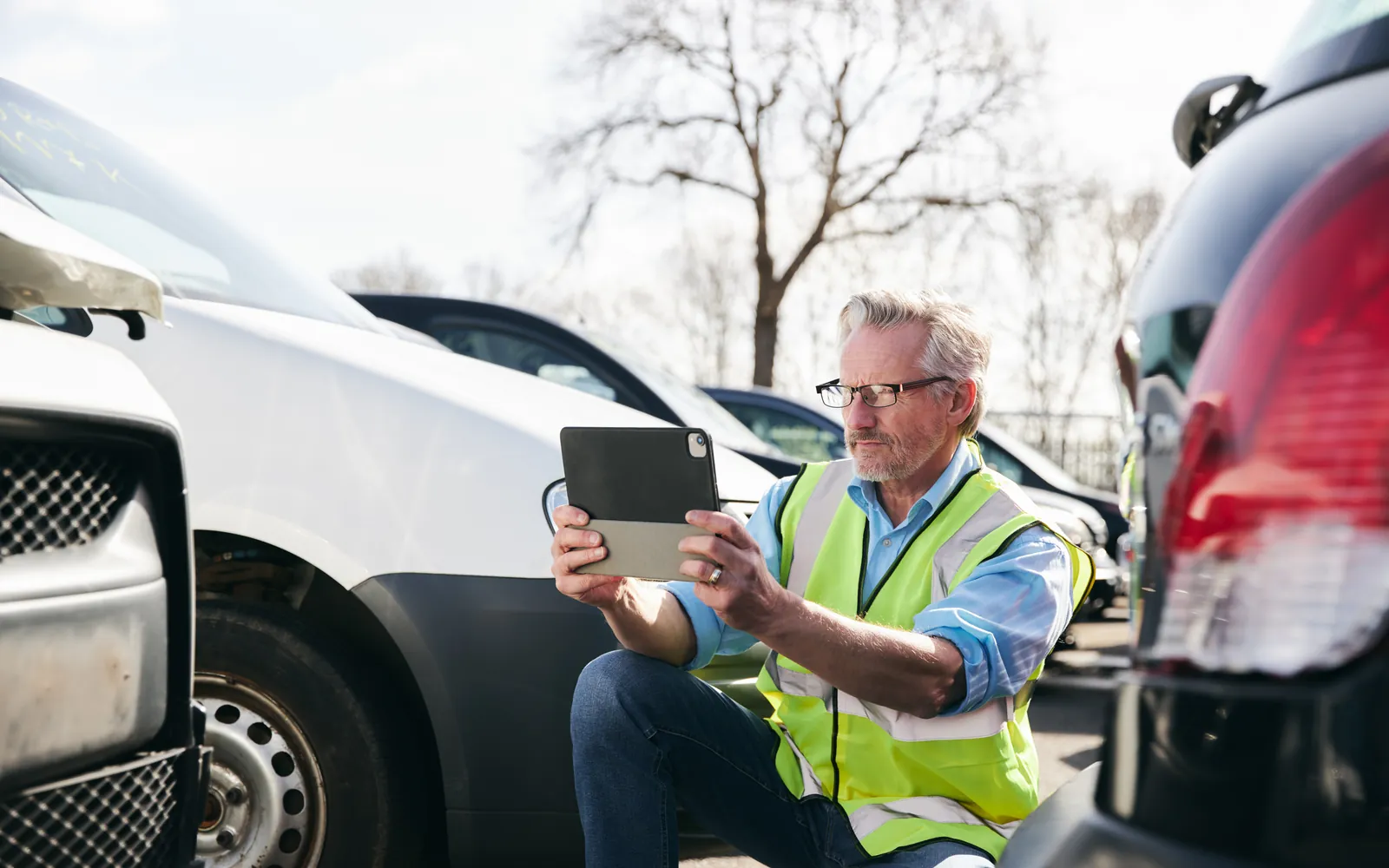 Insurance adjuster photographing vehicle damage with a tablet